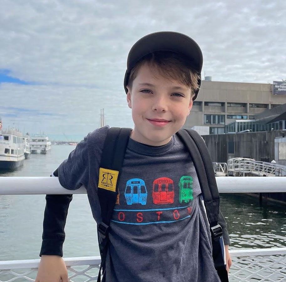 Boy wearing navy blue t-shirt with four Boston Subway vehicles across the chest